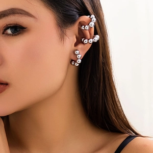 Primo piano di ear cuff e orecchino a sfere in metallo argento lucido indossati