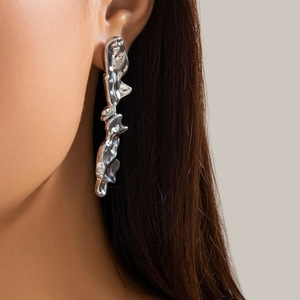 Detail of silver liquid metal lava earrings with irregular texture on a model