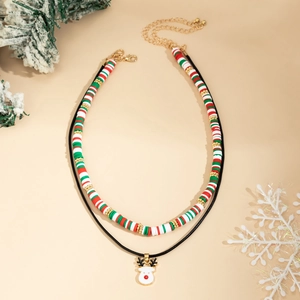Detail of Christmas beaded choker with Heishi beads and reindeer pendant on festive background