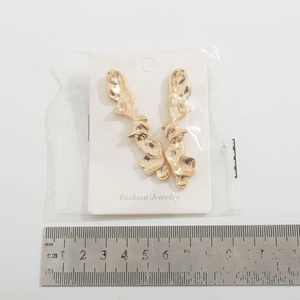 Detailed view of gold lava-style irregular drop earrings with measurement scale