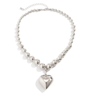 Detailed view of large silver heart pendant and mirror-polished beaded chain necklace