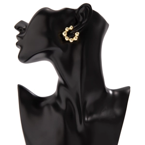 Dettaglio di un ear cuff a cerchio con perline dorate su un modello di ritratto nero