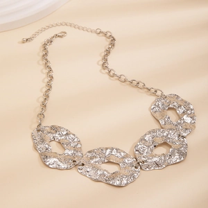 Close-up of industrial silver necklace with irregular hammered metal discs and chunky chain