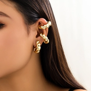 Dettaglio di tre ear cuff in oro a treccia su una modella con finitura lucida a specchio