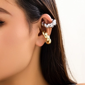 Dettaglio di ear cuff a spirale in oro e argento indossati sul lobo dell'orecchio