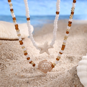 Detail of beach necklaces with starfish and turtle pendants on white and amber beads