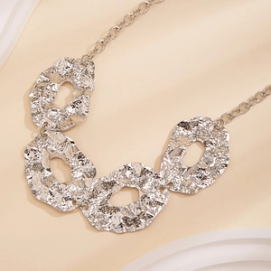 Detail of irregular silver metal plates with hammered texture on a liquid geometry necklace
