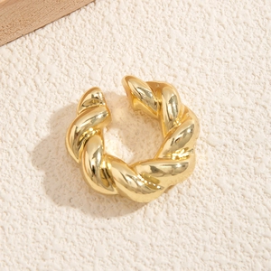 Macro di orecchino a clip dorato stile croissant con design a spirale su sfondo bianco