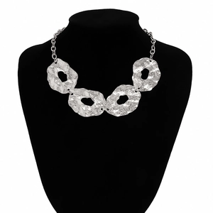 Detailed view of hammered metal irregular circular necklace on black display stand