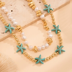 Detail of layered beach necklace with gold beads, white pearls, and turquoise starfish
