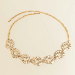 Macro detail of golden irregular hammered metal discs on an adjustable waist chain