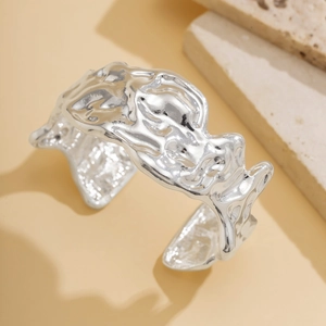 Detailed view of silver liquid metal choker with irregular lava texture on stone surface