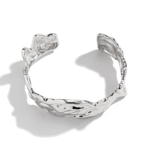 Close-up of silver liquid metal cuff bracelet with irregular wrinkled texture surface