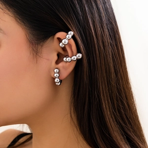 Set di orecchini e ear cuff a sfera d'argento indossati da modella in stile moderno