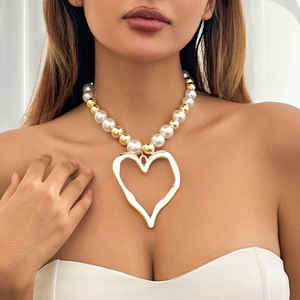 Faux pearl beaded necklace with a large gold hammered hollow heart pendant on a model