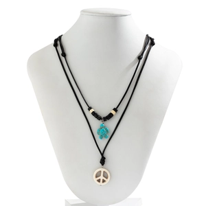 Detail of bohemian layered necklace with turquoise turtle and white peace sign pendant