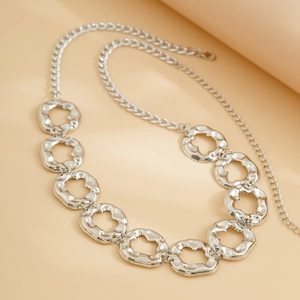 Detail of irregular silver hollow metal discs connected on a fluid geometric chain necklace