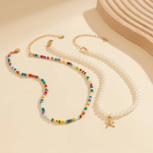 Close-up of a colorful beaded necklace and pearl strand with a gold starfish pendant charm