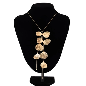 Détail des pendentifs en feuilles de ginkgo dorées avec franges texturées sur collier
