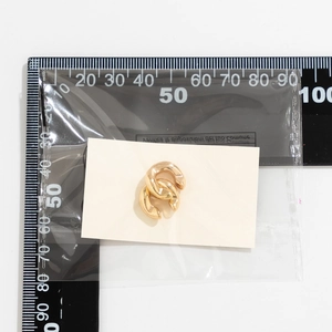 Makroaufnahme von 15 mm goldenen Doppel-Ohrringen mit Größenmessung auf einem Lineal