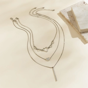 Detail of silver layered necklace showing heart pendant and sleek snake chain bar