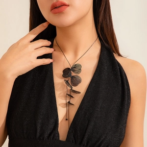 Détail du collier à pampilles en feuilles de ginkgo noires sur une robe à sequins en V