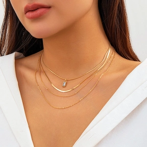 Detailed layered golden necklace set with four chains and a blue gemstone pendant