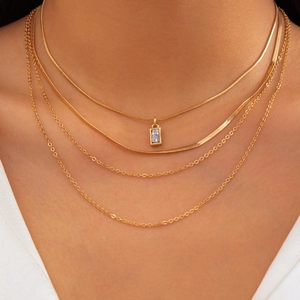 Detail of layered gold snake chains with a rectangular zircon pendant on a model