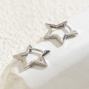 Macro shot of silver star-shaped hoop earrings on textured stone base for women