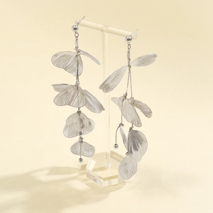 Détail de boucles d'oreilles feuille de ginkgo argentées avec texture évidée sur support