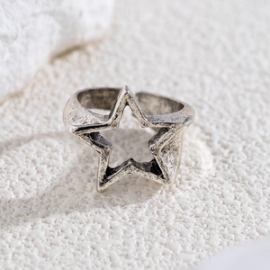 Macro view of vintage silver star ring with distressed texture on white sand background
