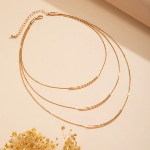 Detailed close-up of triple-layered gold snake chain necklace with curved metal tubes