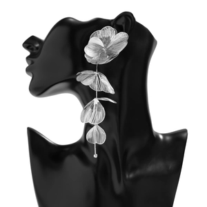 Détail de boucles d'oreilles pendantes en métal argenté à quatre pétales évidés