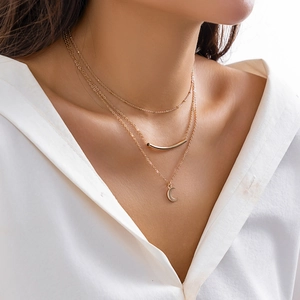 Close-up of triple-layered gold snake bone necklace featuring moon and bar pendants