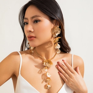 Gros plan d'un collier à pampilles en feuille de ginkgo dorée et de boucles d'oreilles