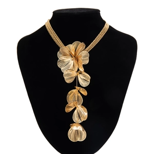 Détail d'un collier feuille de ginkgo doré avec pétales évidés sur un buste noir