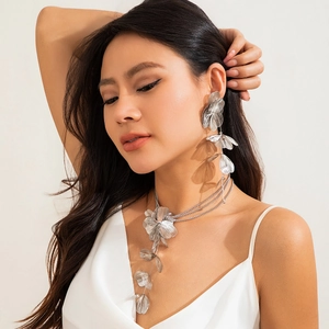 Gros plan d'un collier à pompons en feuilles de ginkgo argentées et boucles d'oreilles