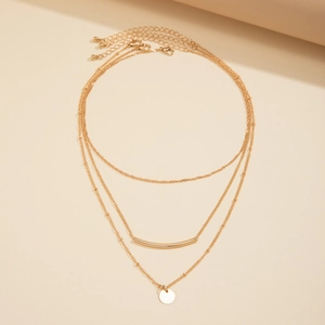 Detailed view of triple-layered gold necklaces with polished bar and disc pendants
