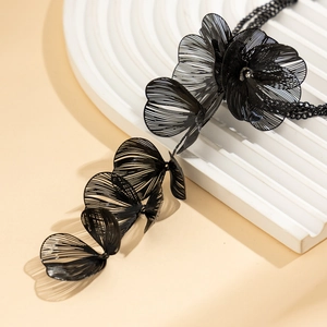 Détail macro du collier feuille de ginkgo noir avec tissage métallique délicat