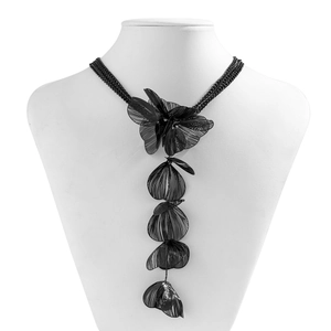 Détail du collier fleur en maille noire avec feuilles à franges sur un buste blanc