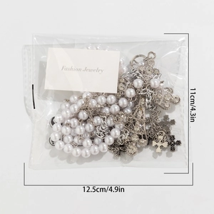 Detail of beaded waist chain with faux pearls and silver cross pendants in packaging