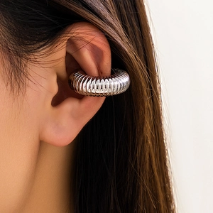 Vista macro di un earcuff a costine argentato sulla cartilagine dell'orecchio moderno
