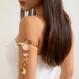 Détail d'un brassard floral doré avec des pétales texturés et de longs pendentifs en métal