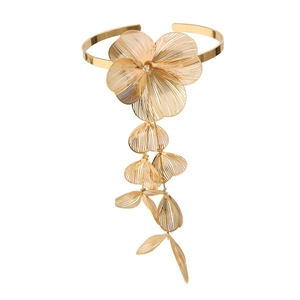 Détail d'un bracelet de bras doré avec fleur ajourée et pompons de feuilles ciselées