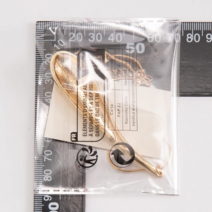 Détail macro du pendentif goutte d'or avec texture brossée sur une règle graduée