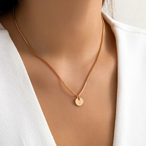 Close-up of gold pendant necklace with engraved letter D on a delicate box chain