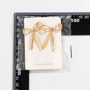 Detaillierte Messung der goldenen Schleifen-Ohrstecker auf Displaykarte mit Lineal