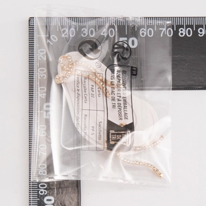 Makroaufnahme von vergoldeten Schleifenohrringen mit Zirkonia auf einem Messlineal