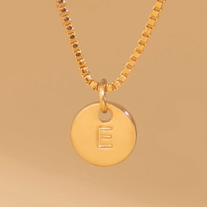 Detailed close-up of a gold box chain necklace with an engraved letter E round pendant