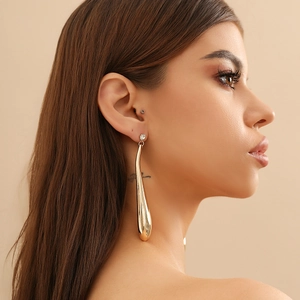 Gros plan d'une boucle d'oreille goutte dorée avec zircon sur l'oreille du mannequin